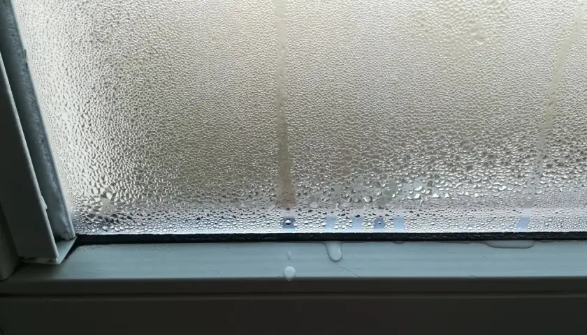 Goccioline d'acqua su un vetro, un fenomeno che illustra il concetto di traspirante significato, con condensa che scivola sul davanzale.