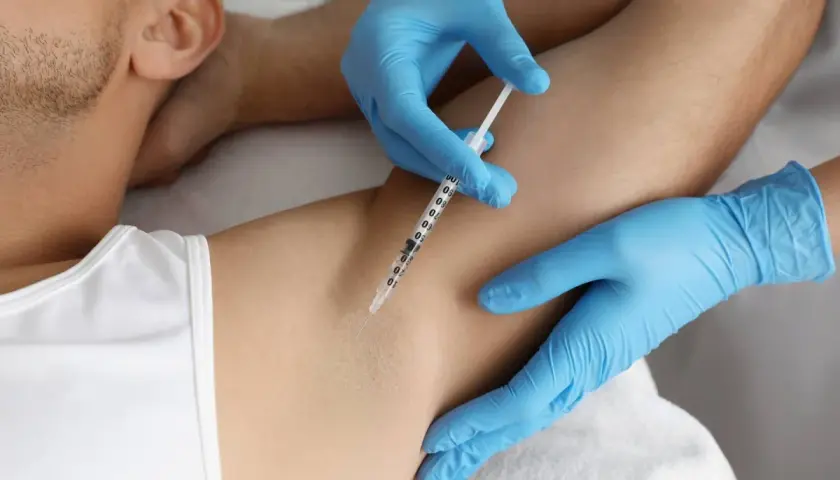 En person får botox mot svett i armhålan. En spruta injicerar vätska under huden.