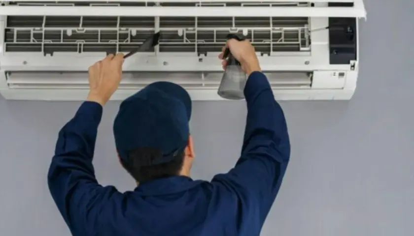 Técnico limpiando un aire acondicionado, paso clave para saber como se instala un aire acondicionado correctamente y mantenerlo.