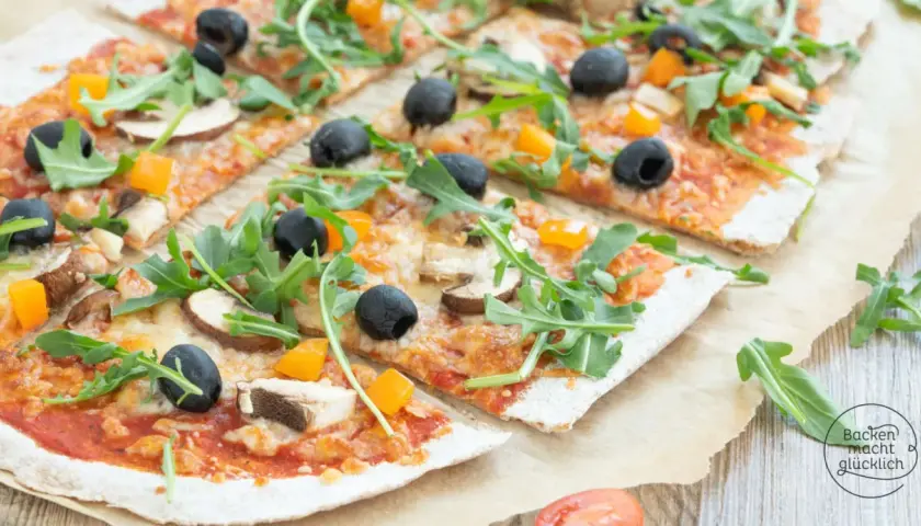 Eine leckere vollkorn pizza mit Pilzen, Oliven und Rucola, belegt mit geschmolzenem Käse und Paprikawürfeln.