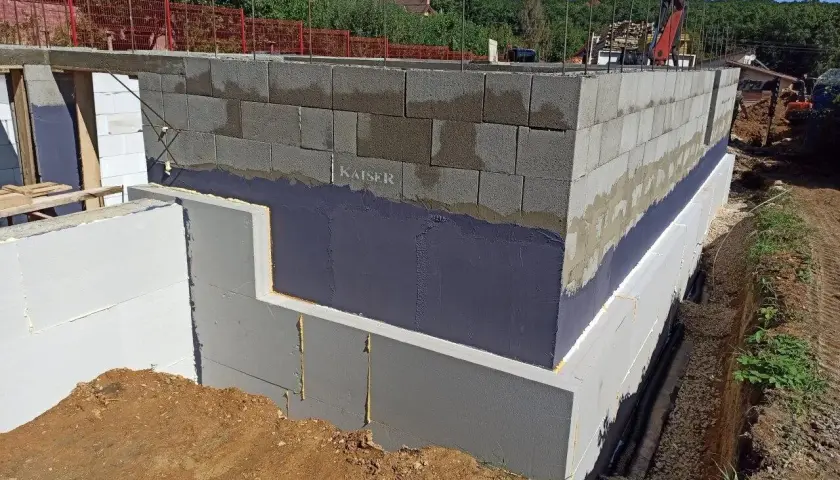 Fundament budynku z bloków betonowych zabezpieczony hydroizolacją. Widoczna izolacja termiczna i przeciwwilgociowa.