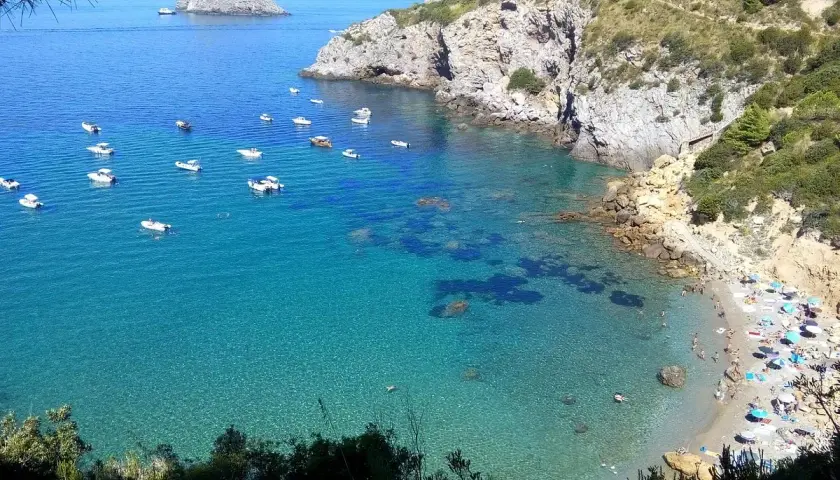 Ein **Geheimtipp Toskana Strand**: Türkisblaues Wasser, kleine Boote und ein sonniger Strand mit bunten Sonnenschirmen. Ein idyllischer Ort zum Entspannen.