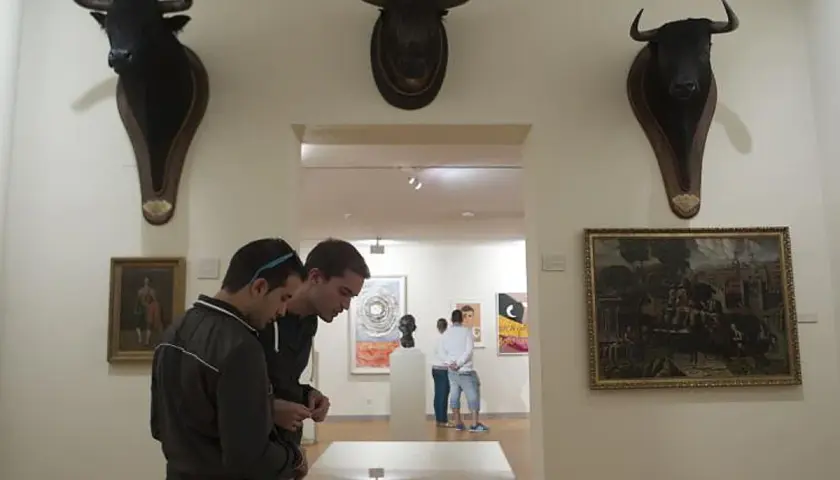 Dos jóvenes observan cabezas de toro disecadas en el museo taurino de Madrid.