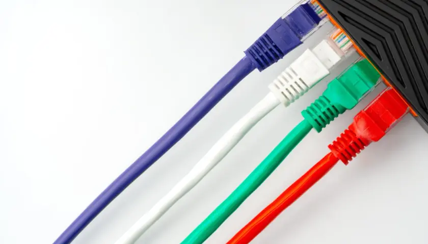 Cables de red de colores (morado, blanco, verde, rojo) conectados a un dispositivo.