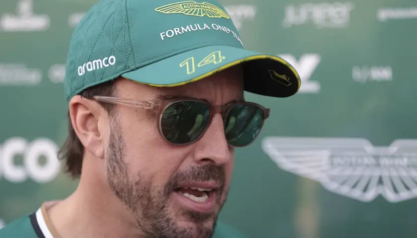 Fernando Alonso trägt eine Aston Martin Kappe und Sonnenbrille. Sein Gehalt bei Aston Martin ist ein heiß diskutiertes Thema.