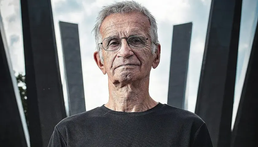 Portret starszego mężczyzny w okularach na tle nowoczesnej architektury.