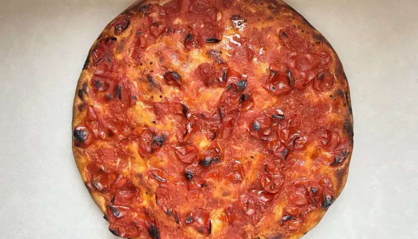 Focaccia rossa con pomodorini succosi e crosta dorata, un'esplosione di sapore mediterraneo.