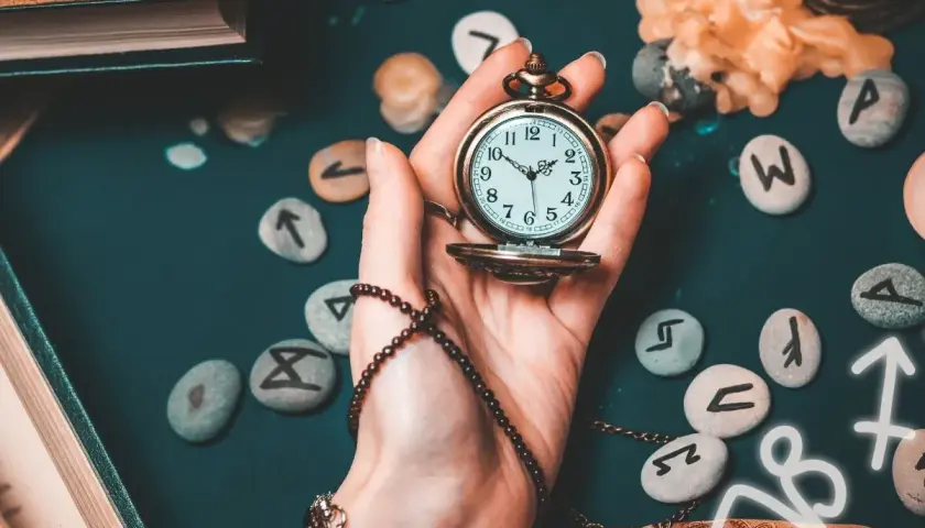 Dłoń trzyma kieszonkowy zegarek, wokół kamienie z runami i symbole astrologiczne. Czas ma wielkie **znaczenie** w 1919 roku, gdy świat się zmienia.