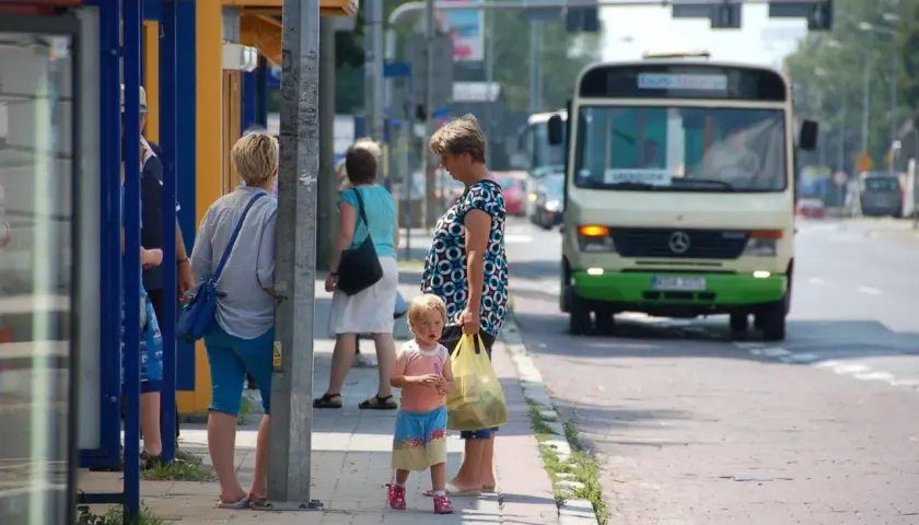 Ludzie czekający na autobus na przystanku, w tle autobus.