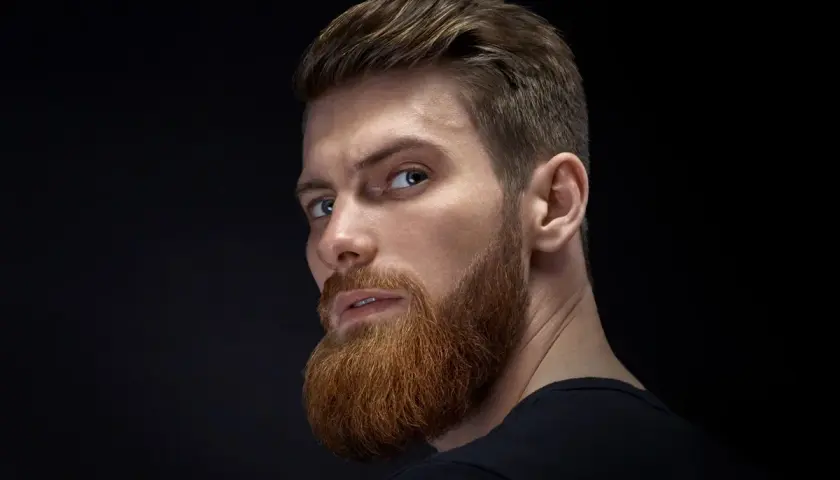Hombre con barba y peinado moderno, ejemplo de cortes de pelo hombre elegante.
