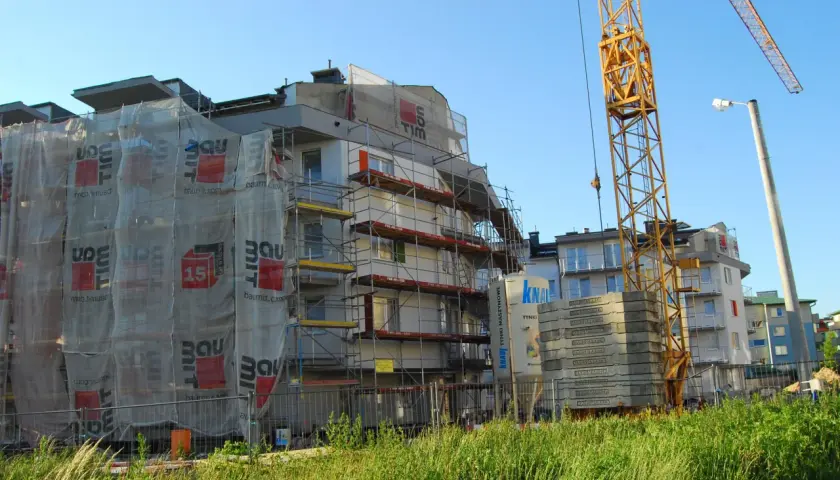Budowa bloku mieszkalnego z żurawiem i rusztowaniami. Zastanawiasz się, ile deweloper zarabia na domu?