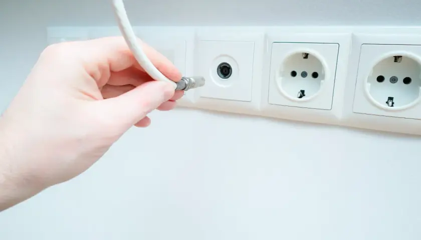 Dłoń podłącza kabel do gniazdka antenowego. Pytanie: jaki kabel do anteny naziemnej?