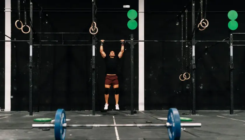 Mężczyzna wykonuje podciąganie na drążku w siłowni CrossFit.