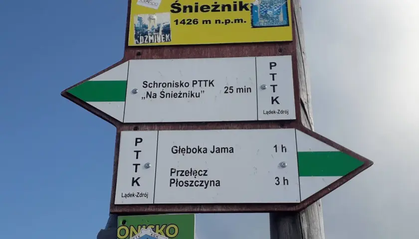 Znaki szlakowe na masywie Śnieżnika wskazują drogę do schroniska i na przełęcz.