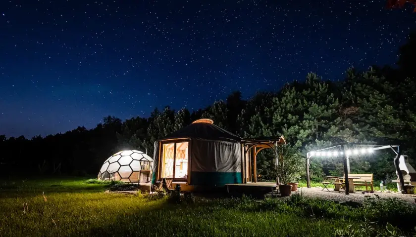 Nocne niebo pełne gwiazd nad jurtą i kopułą. Idealne klimatyczne miejsca na weekend we dwoje, z oświetlonym tarasem i grillem.
