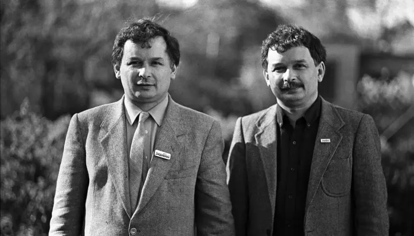 Dwóch mężczyzn w garniturach, jeden z przypinką "Solidarność".