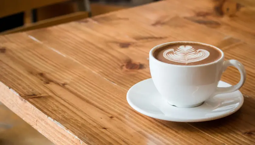 Biała filiżanka z kawą flat white, ozdobiona latte art. Dowiedz się, jak zrobić flat white w domu.