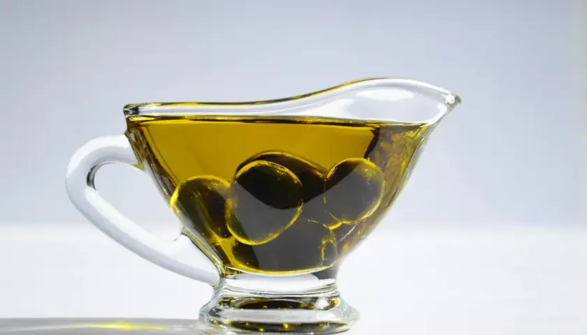 Aceite de oliva para el pelo en una salsera de cristal con aceitunas. Un ingrediente natural para un cabello radiante.