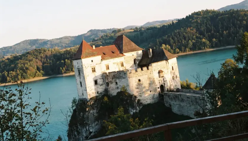 Niedzica-zamek trasa: malowniczy zamek na skale nad turkusową wodą, otoczony zielonymi wzgórzami.