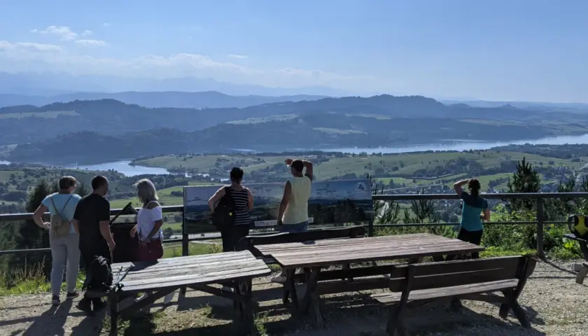 Widok z góry Wdżar na jezioro i góry. Grupa turystów podziwia panoramę.