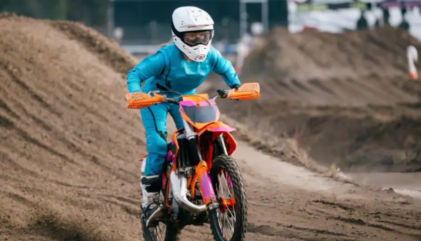 Piloto en moto 50cc azul y naranja compite en circuito de tierra. ¡Sorprende cuanto corre una 50cc!