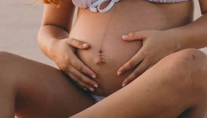 Ventre de femme enceinte avec une ligne brune visible, signe de grossesse. La ligne brune grossesse quel mois est souvent plus marquée vers le 5ème mois.