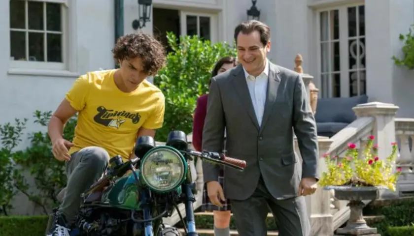 Un ragazzo su una moto e un uomo in giacca e cravatta sorridono. Le recensioni di "Your Honor" potrebbero descrivere questa scena.