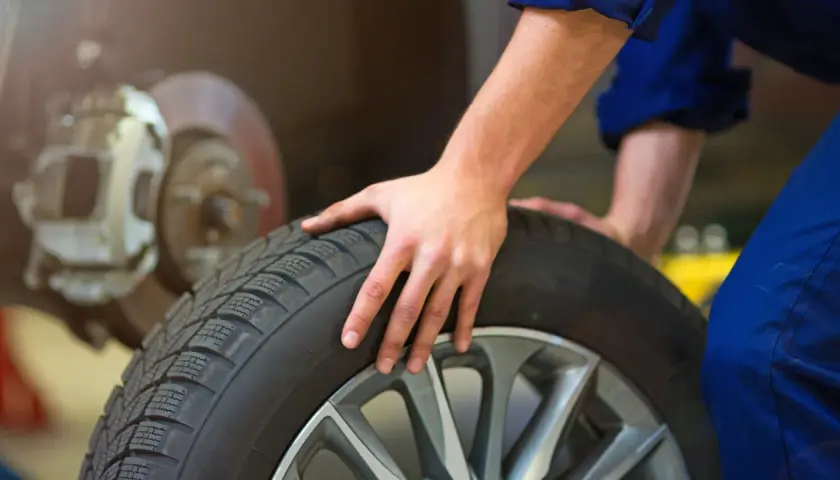 Mecánico revisa un neumático, pensando cuánto duran las ruedas de un coche.