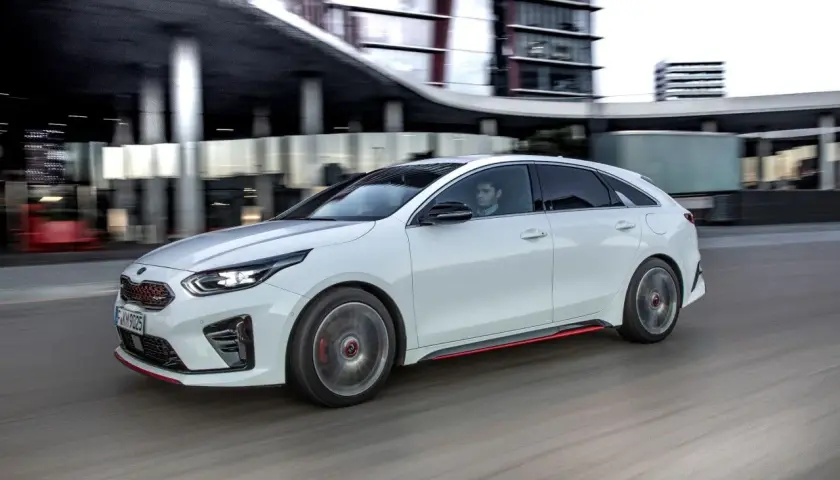 Biały Kia Ceed w ruchu miejskim, z widocznym kierowcą. Zwróć uwagę na rozmiar opon, idealny do dynamicznej jazdy.