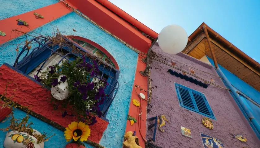 Coloratissimi edifici a Vietri sul Mare: cosa vedere? Finestre fiorite, decorazioni marine e un cielo azzurro.