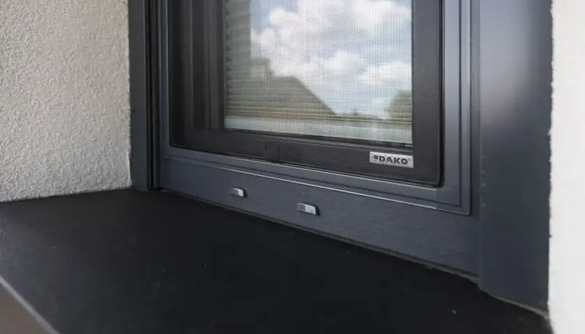 Szary parapet zewnętrzny pod oknem z moskitierą. Zastanawiasz się, czym przykleić parapet zewnętrzny blaszany?