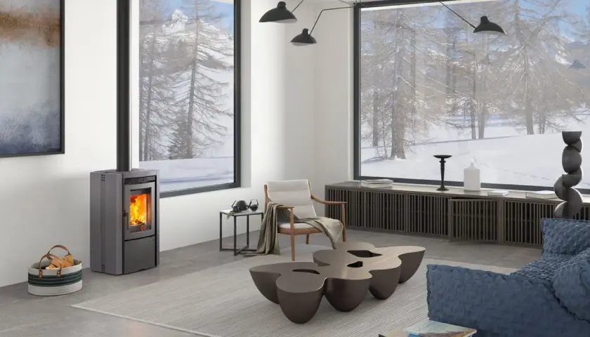 Estufa de pellets moderna en un salón acogedor con vistas nevadas. ¿Qué tipo de estufa es mejor para crear este ambiente cálido?
