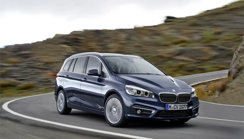 Un BMW Serie 2 Gran Tourer azul oscuro en una carretera sinuosa. A pesar de su diseño, algunos propietarios han reportado problemas.
