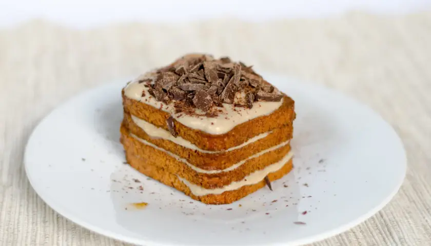 Una deliziosa torta tiramisù a più strati, ricoperta di crema e scaglie di cioccolato fondente.