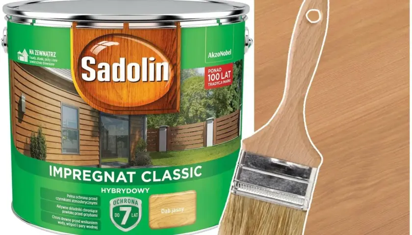 Puszka Sadolin Impregnat Classic w kolorze Dąb Jasny, obok pędzla na tle drewnianej podbitki.