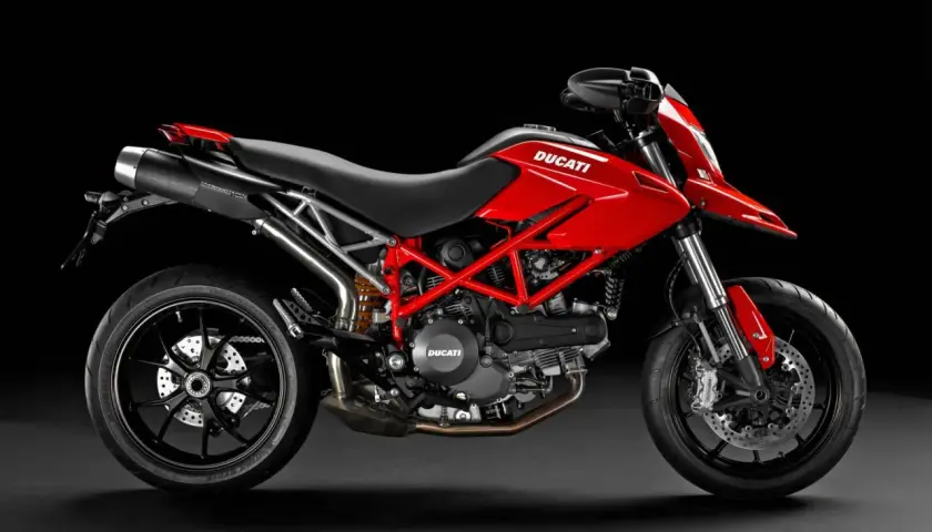 Czerwony Ducati Hypermotard 796 z czarnymi felgami i wydechem, gotowy do jazdy po miejskich ulicach.