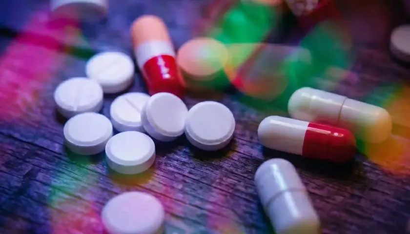 Pastiglie e capsule colorate su un tavolo di legno. L'aripiprazolo a cosa serve? Aiuta a trattare disturbi come schizofrenia e disturbo bipolare.