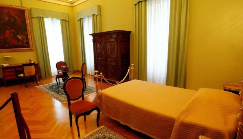 Ein Schlafzimmer, das einst die papst wohnung war, mit einem Bett, einem Schrank und einem Schreibtisch.
