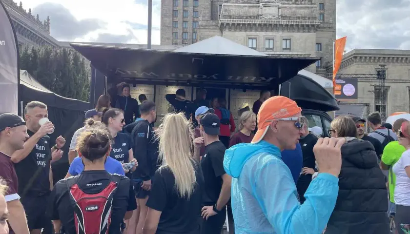 Grupa biegaczy przed budynkiem, dyskutują, czy można biegać codziennie. Na koszulkach napis "Run your way".