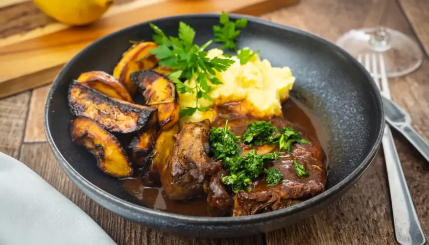 Ein Teller mit Ossobuco, dazu Kartoffelpüree und geröstete Kartoffelspalten. Dieses Ossobuco Rezept original italienisch ist ein Genuss!