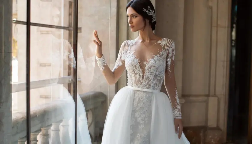 Elegancka panna młoda w sukni z koronki i tiulu, z ozdobną biżuterią we włosach. Inspiracja dla fryzur na ślub.