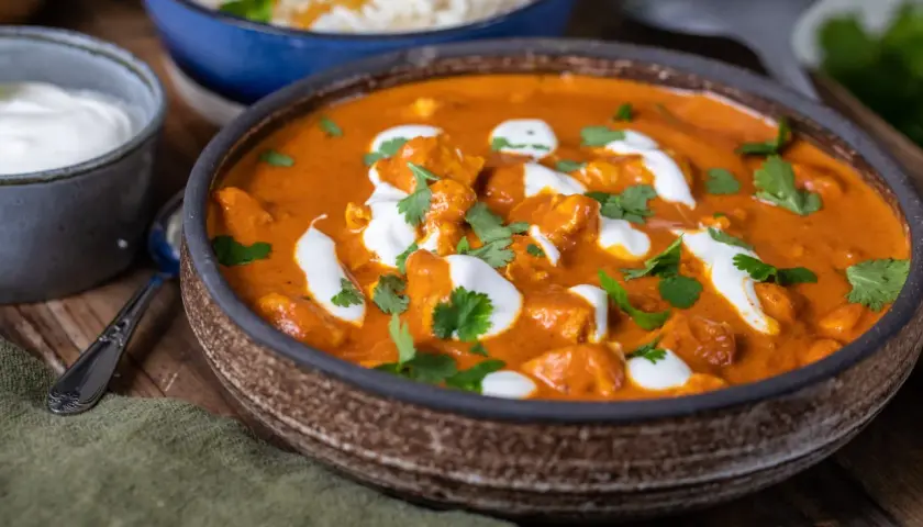 En krämig kyckling tikka masala med ris och en klick gräddfil.