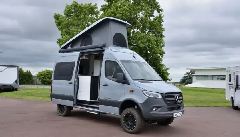 Le plus grand fourgon aménagé, un Mercedes gris avec toit relevable, prêt pour l'aventure.
