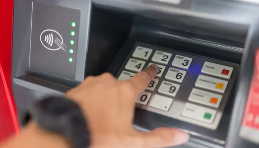 Une main tape un code sur un clavier de distributeur. Comment retrouver son code de carte bancaire ? La sécurité avant tout.