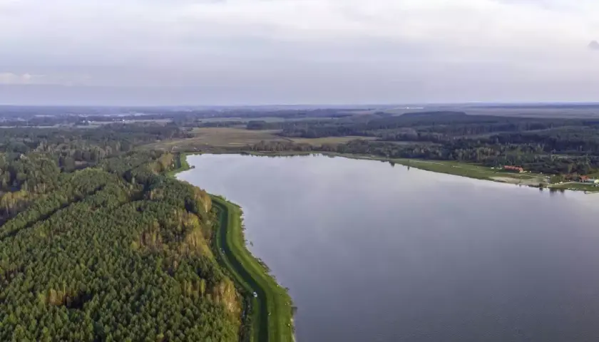 Rozległy zalew Biszcza otoczony lasem i zielonymi łąkami. Spokojna tafla wody odbija niebo.