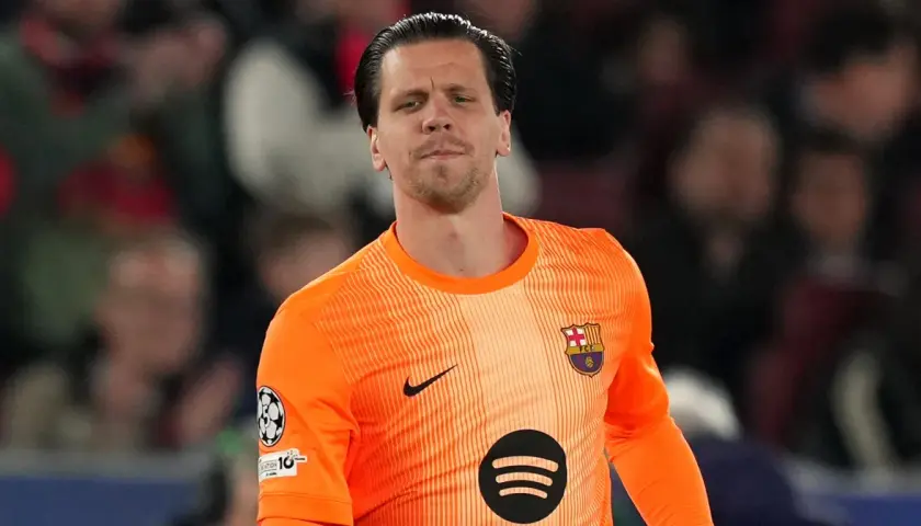 Bramkarz w pomarańczowej koszulce FC Barcelona, z herbem klubu na piersi. To właśnie w tym klubie gra Szczęsny.