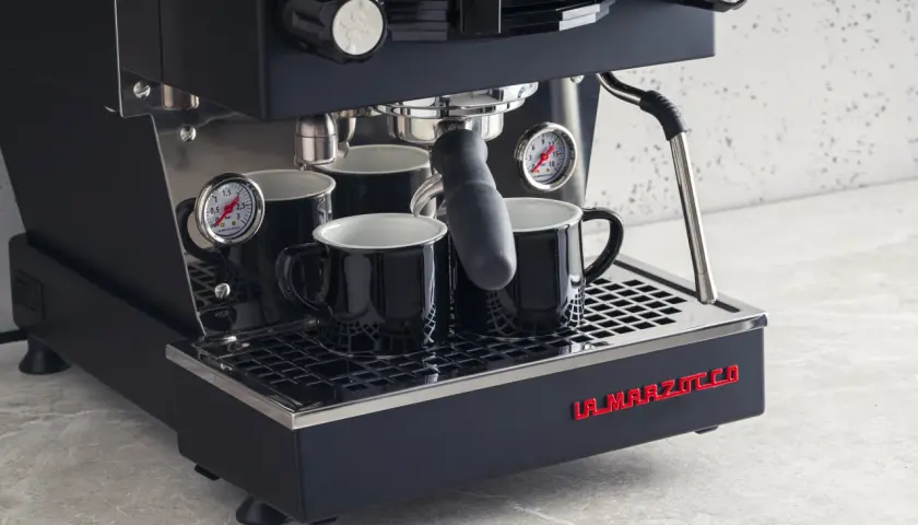 Profesjonalny ekspres do kawy La Marzocco z dwoma czarnymi filiżankami. Dowiedz się, jak odpowietrzyć ekspres Delonghi, by cieszyć się idealnym espresso.