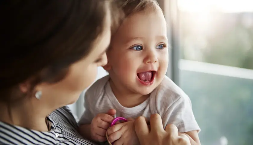 Bambino sorridente con la mamma, forse è l'inizio della lallazione.