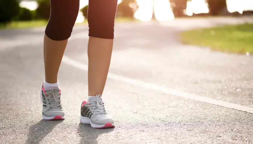 Kobieta w sportowych butach biegnie po asfalcie. Czy bieganie odchudza? Tak, regularny wysiłek fizyczny pomaga spalać kalorie i kształtować sylwetkę.