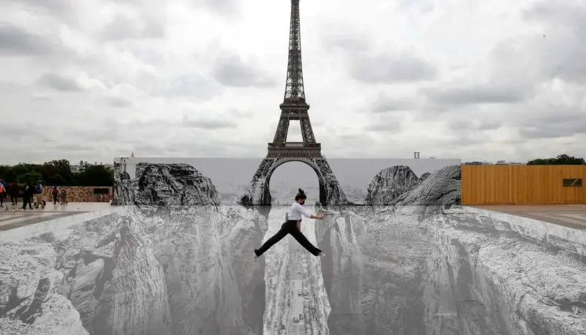 Une femme saute au-dessus d'un gouffre peint au sol, devant la Tour Eiffel. Un **tableau trompe l'oeil** saisissant.